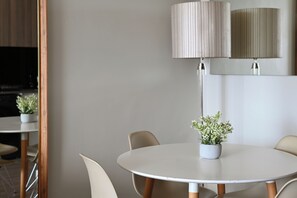 A round dining table with chairs, a potted plant, and a wall-mounted lamp. - Cityscape Luxury Studio with Balcony, AC in Cape Town (Cape Town)