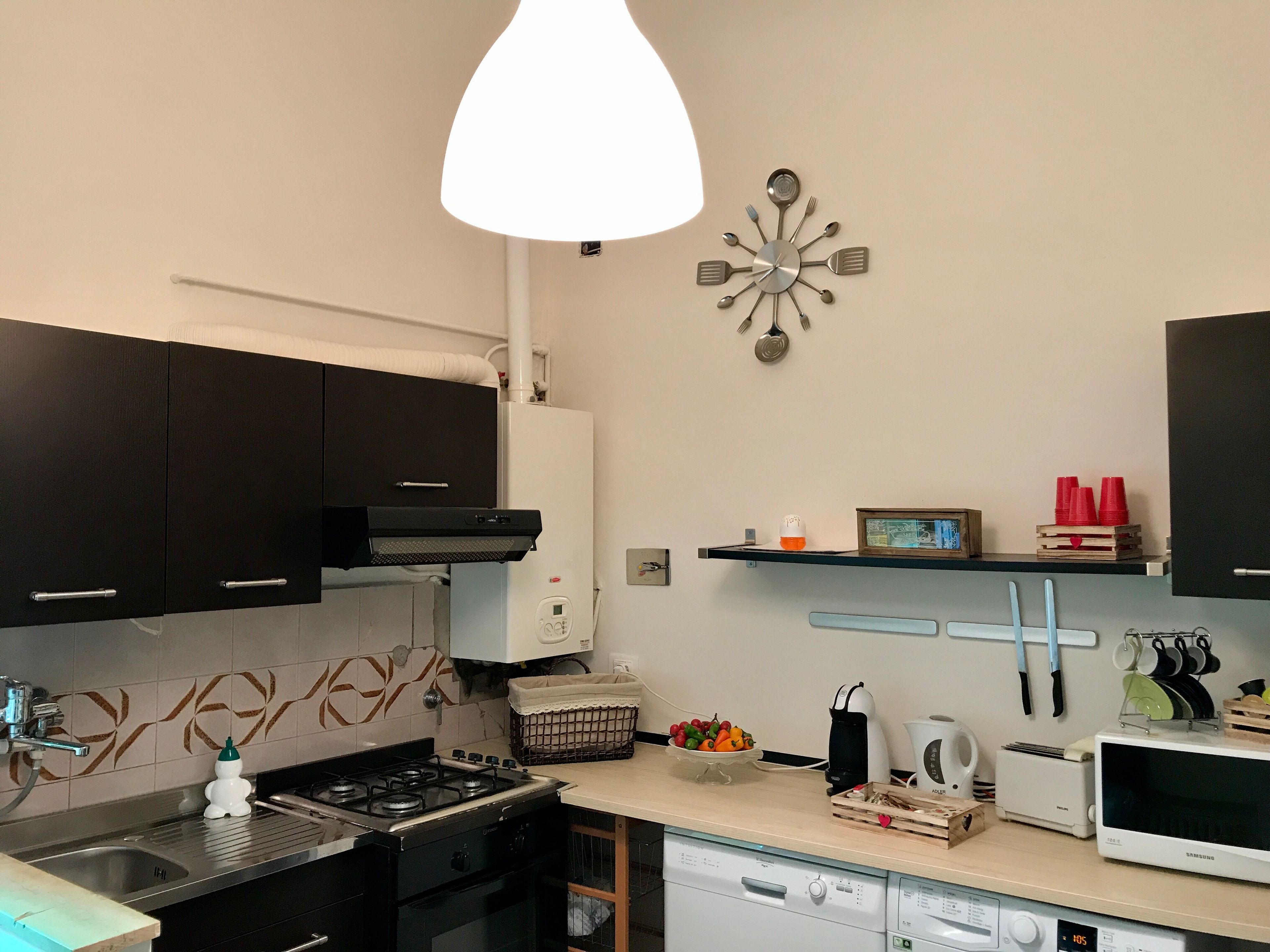 A modern kitchen with a gas stove, dishwasher, microwave, and a decorative wall clock.