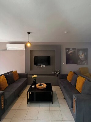A modern living room with two sofas, a coffee table, a flat-screen TV, and artwork on the walls. - 2-Bedroom in Central Pendik, Turkey (Pendik)