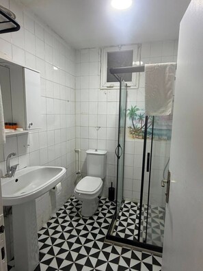 A bathroom with a white sink, toilet, and a shower with a glass door. - 2-Bedroom in Central Pendik, Turkey (Pendik)