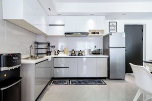 A modern kitchen with white cabinetry, a stainless steel refrigerator, and a coffee machine. - 1-Bedroom Apartment with Nairobi National Park Views (Nairobi)