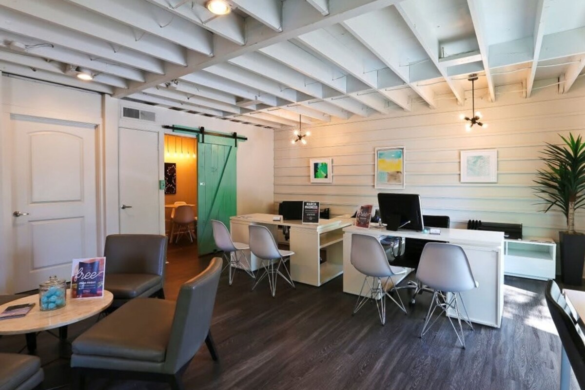 A modern office space with a reception desk, seating area, and a door leading to another room.
