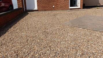 A residential building with a gravel driveway, a garage, and a brick facade.