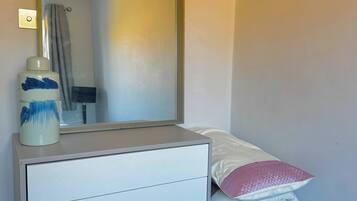 Une chambre à coucher avec un lit, une commode, un miroir et une table de chevet.