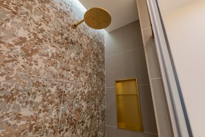A bathroom with a shower area featuring a mosaic tile wall and a gold showerhead. - San Francesco Boutique House by Wonderful Italy (Turin)