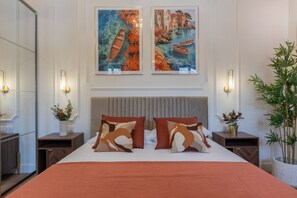 A hotel room with a large bed, two nightstands, a modern headboard, and two wall-mounted paintings. - San Francesco Boutique House by Wonderful Italy (Turin)