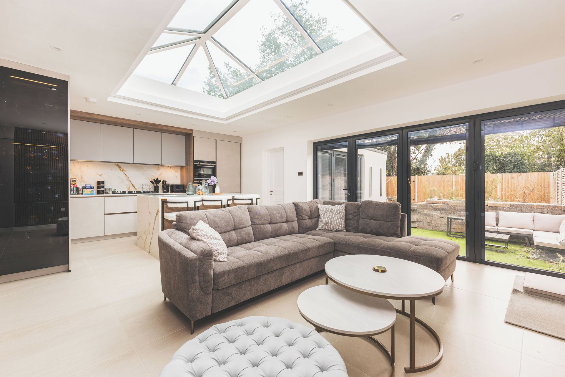 A modern living room with a sectional sofa, a round coffee table, and a glass dining area.