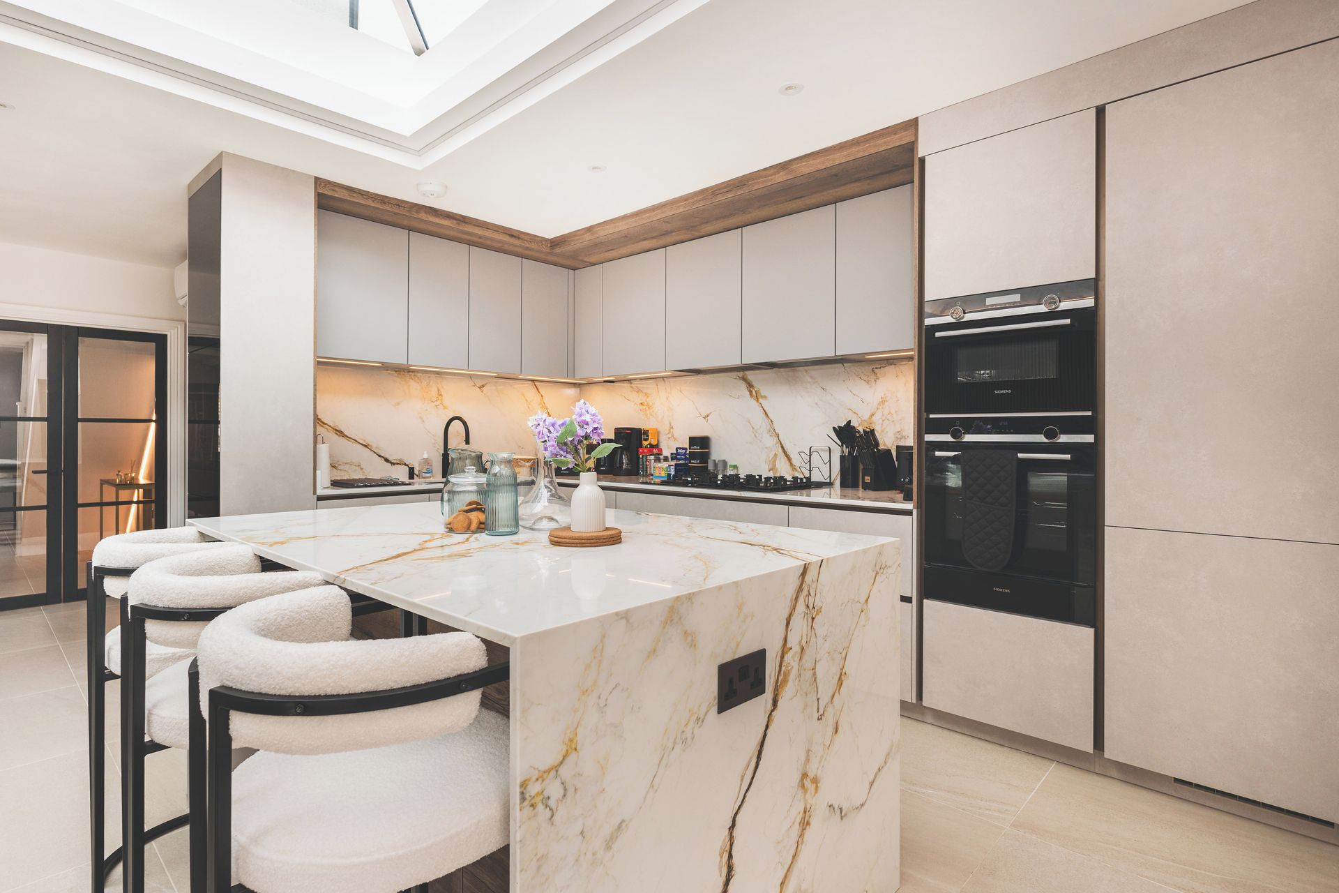 A modern kitchen with a marble island, built-in appliances, and a skylight.