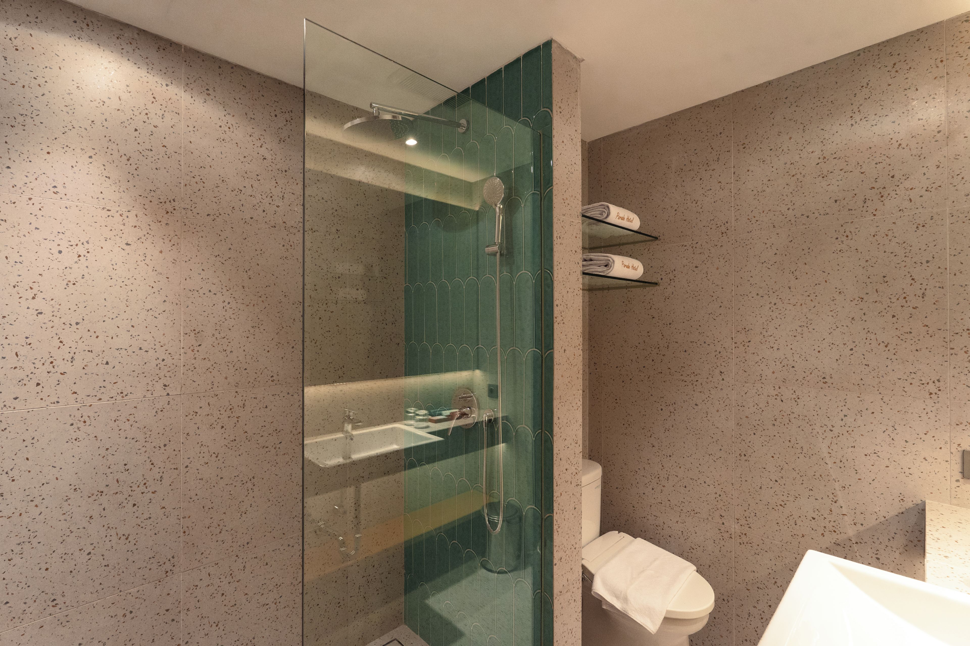 Un baño moderno con ducha de vidrio, lavamanos e inodoro.