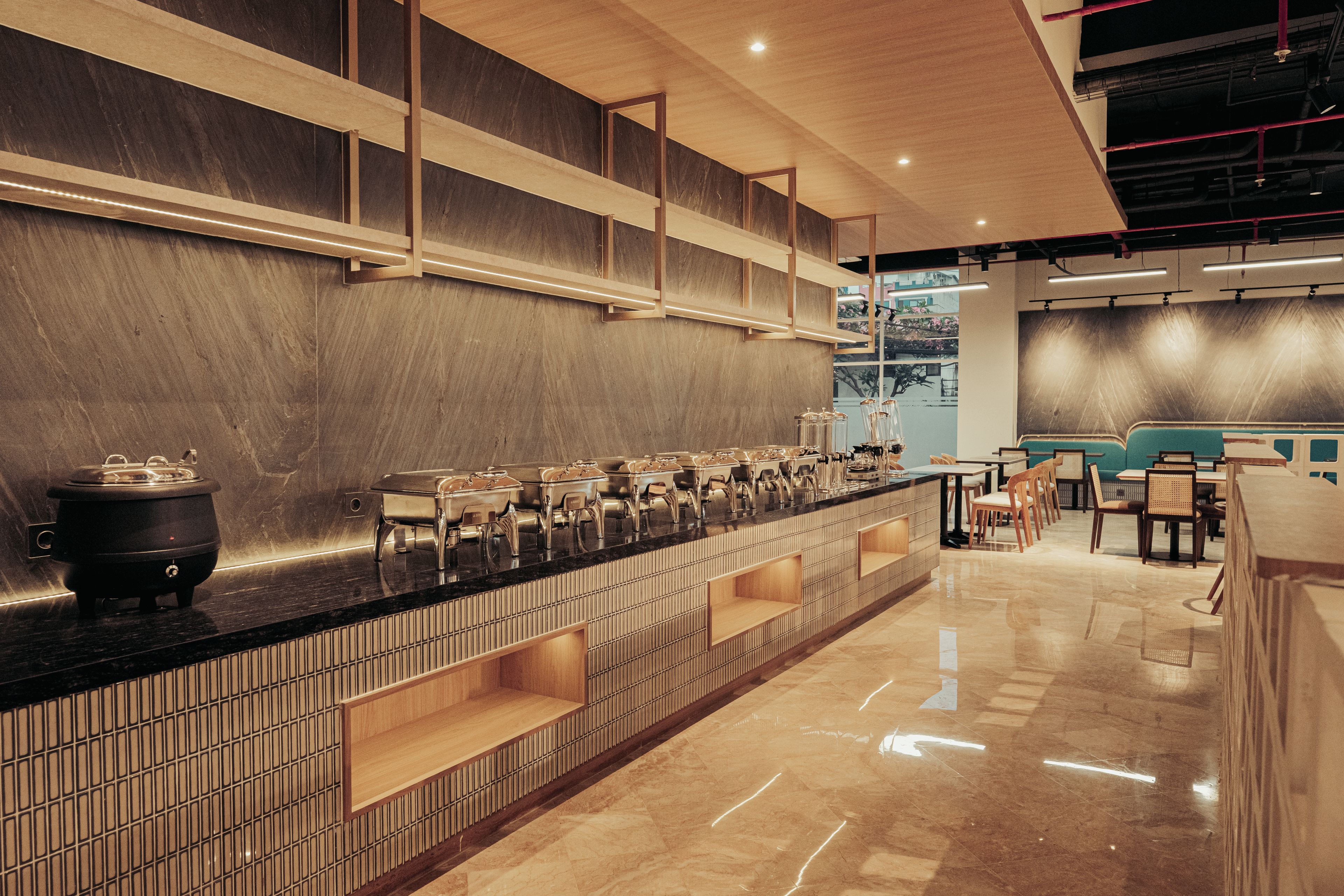 Un bar moderno con una barra alargada, diversas opciones de asiento y vistas a la ciudad a través de amplios ventanales.