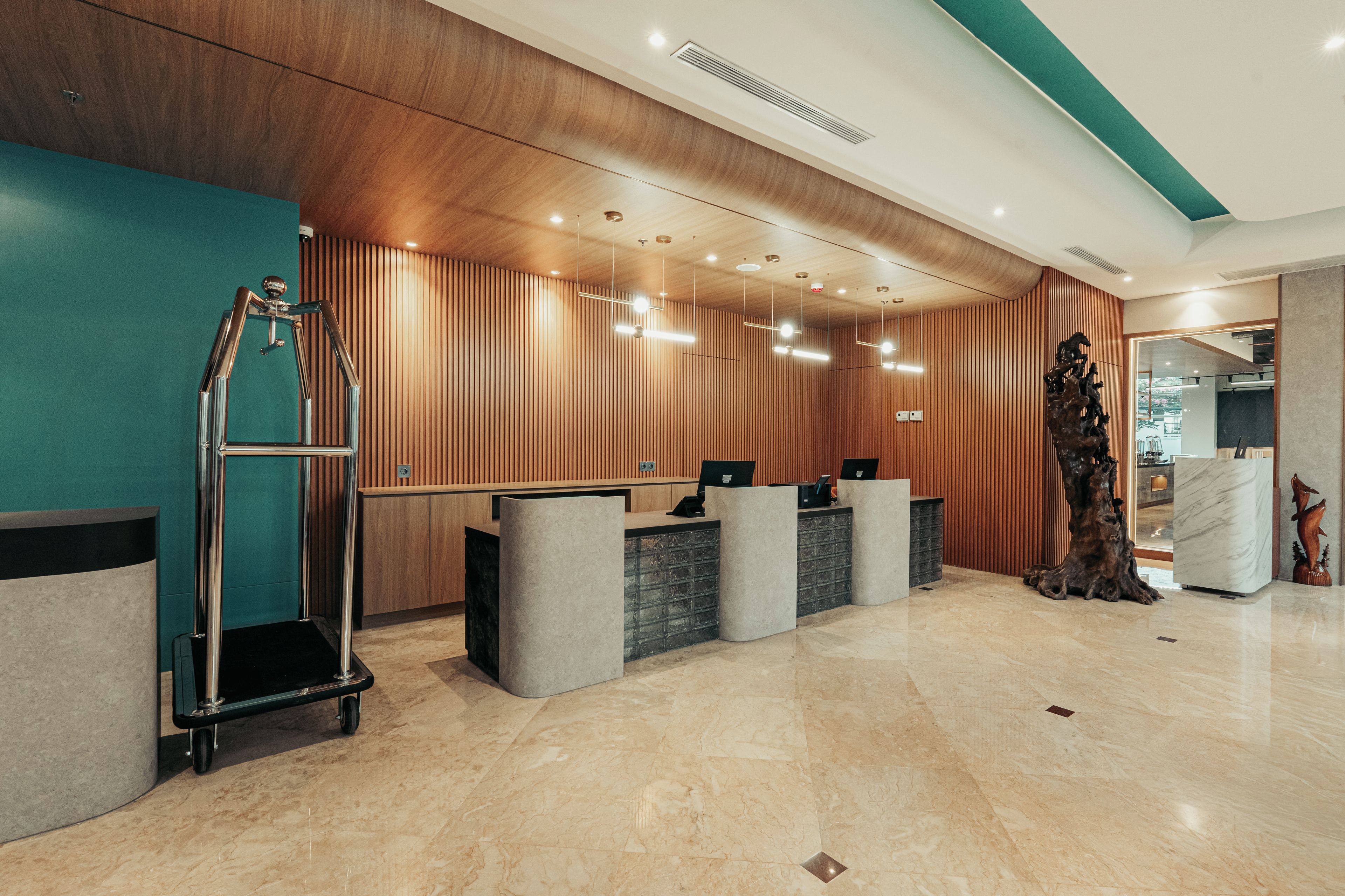 Un área de recepción con un revestimiento de panel de madera, un mostrador de recepción, un carrito metálico y un piso de mármol.