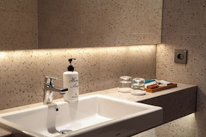 A bathroom with a white sink, a soap dispenser, and a tray with toiletries. - Parade Hotel Jakarta (Jakarta)