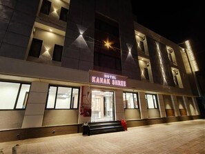 Et hotel med en moderne facade, oplyst skiltning og en velbelyst indgang.