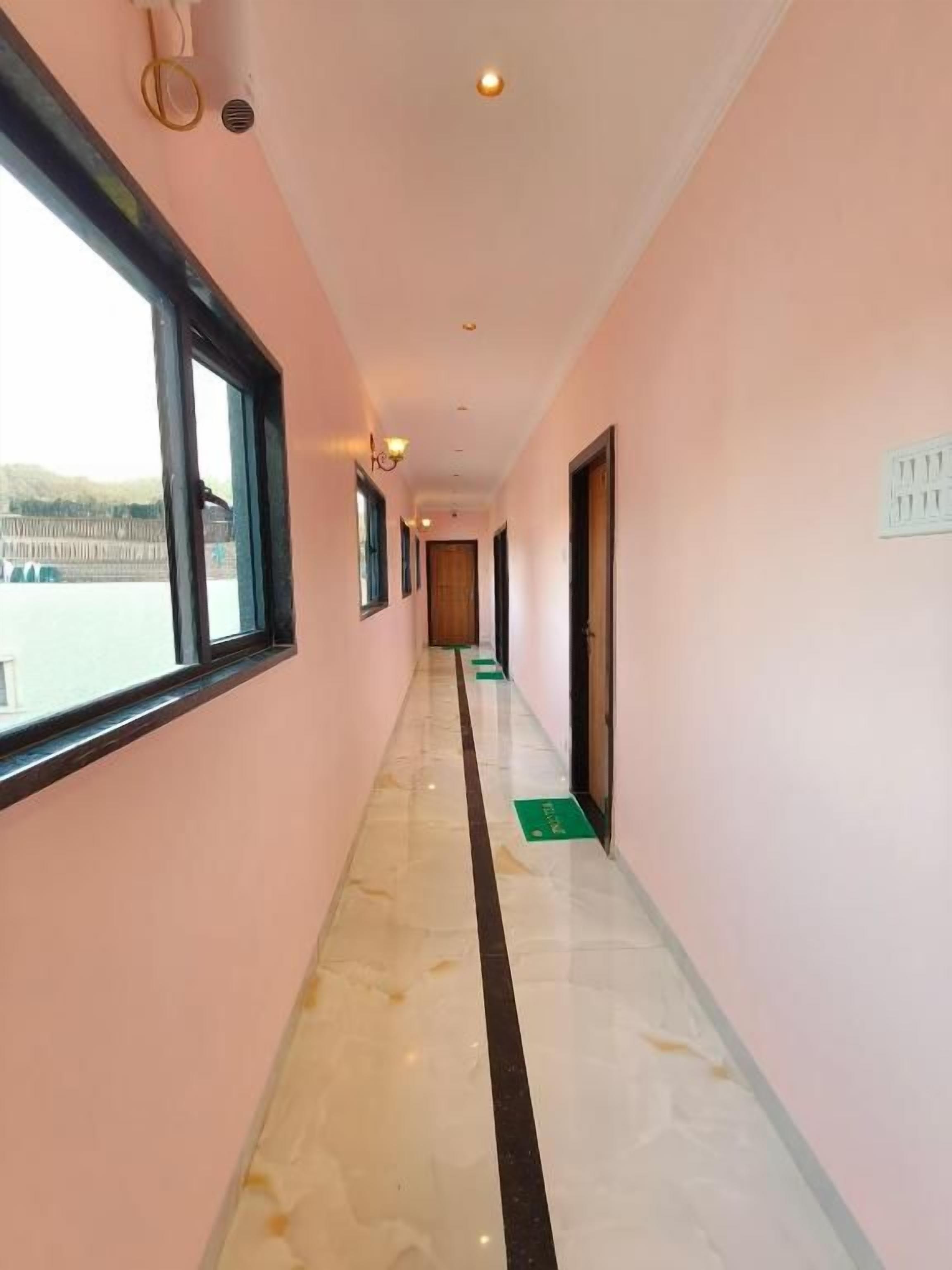 A corridor with a marble floor, a window on the left, and a door on the right.
