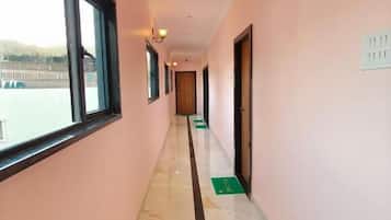 A corridor with a marble floor, a window on the left, and a door on the right.