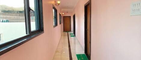 A corridor with a marble floor, a window on the left, and a door on the right.