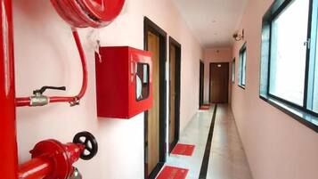 A hallway with a fire hose reel, a red fire alarm box, and a window on the right.