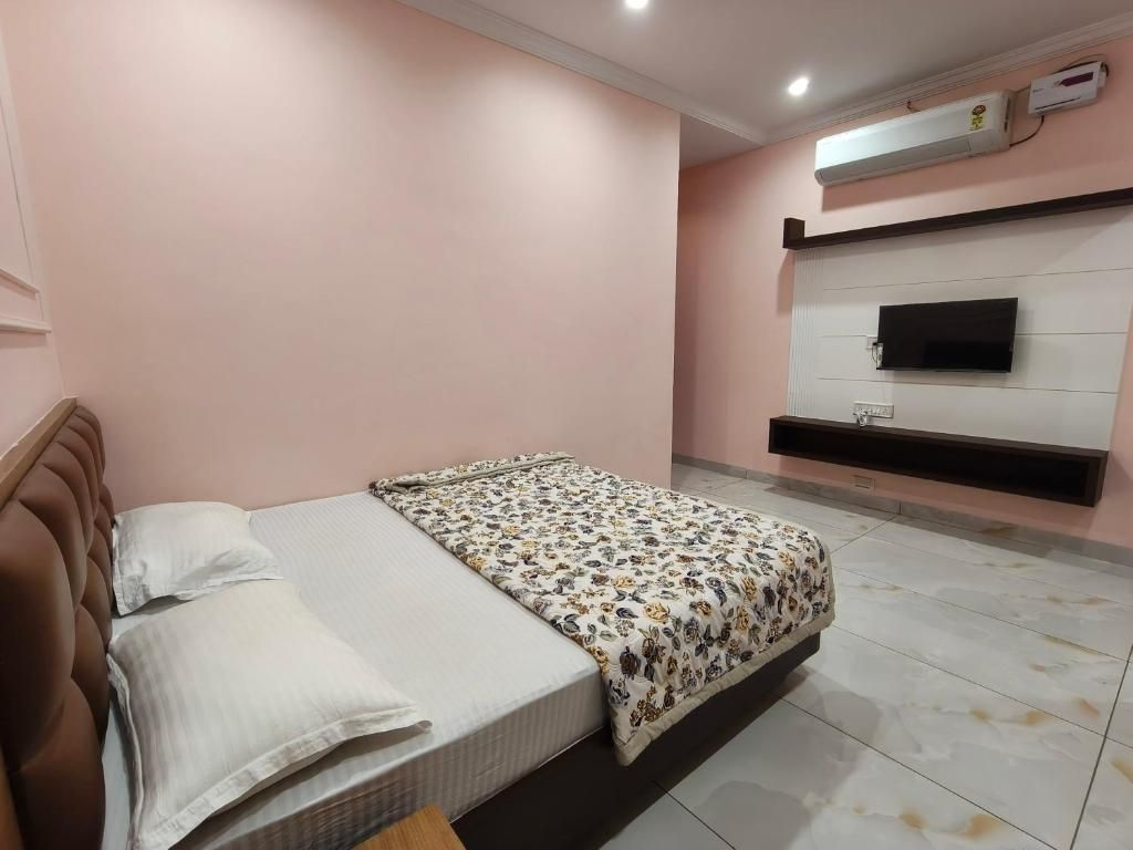 A bedroom with a bed, a flat-screen TV mounted on the wall, and a built-in air conditioning unit.