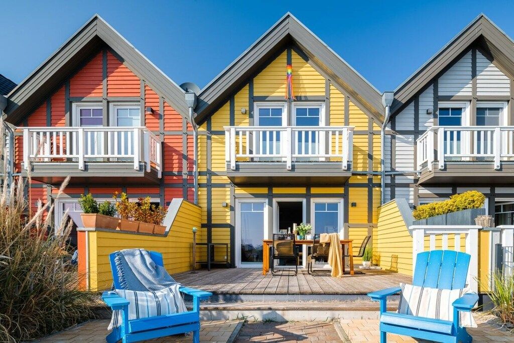 A row of colorful houses with balconies, a wooden deck, and outdoor seating.