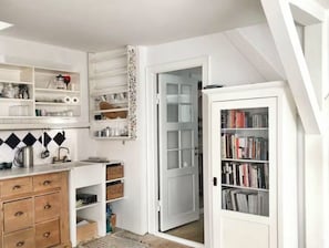 A compact kitchen with white cabinetry, a wooden countertop, and a built-in bookshelf. - Bohemian rooftop flat with shared terrace in the heart of pictoresque Nyhavn (København)