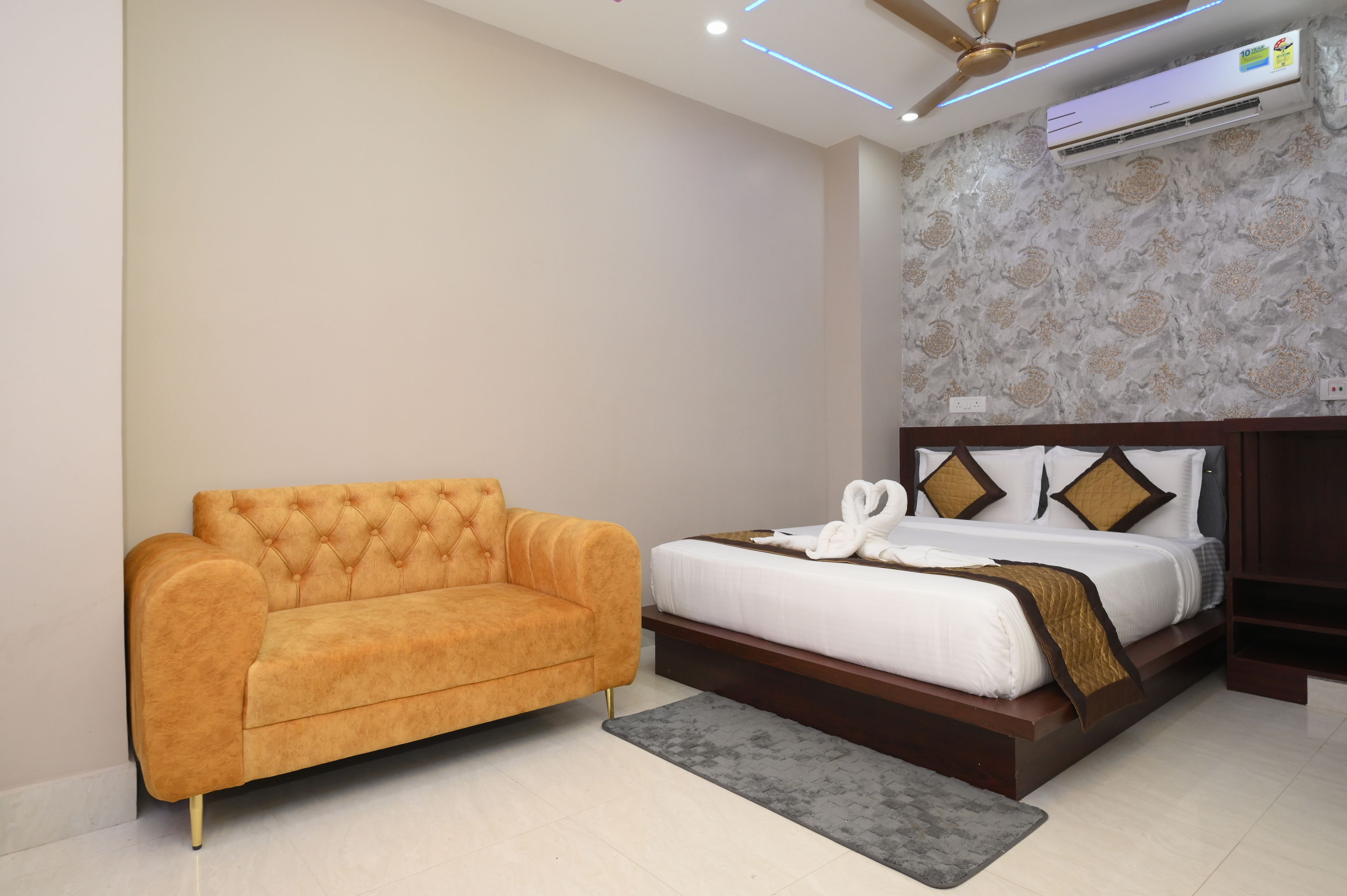 Una habitación de hotel con cama, sofá, ventilador de techo y aire acondicionado.