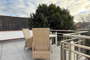 Ein Balkon mit Korbstühlen und einem Metallgeländer.