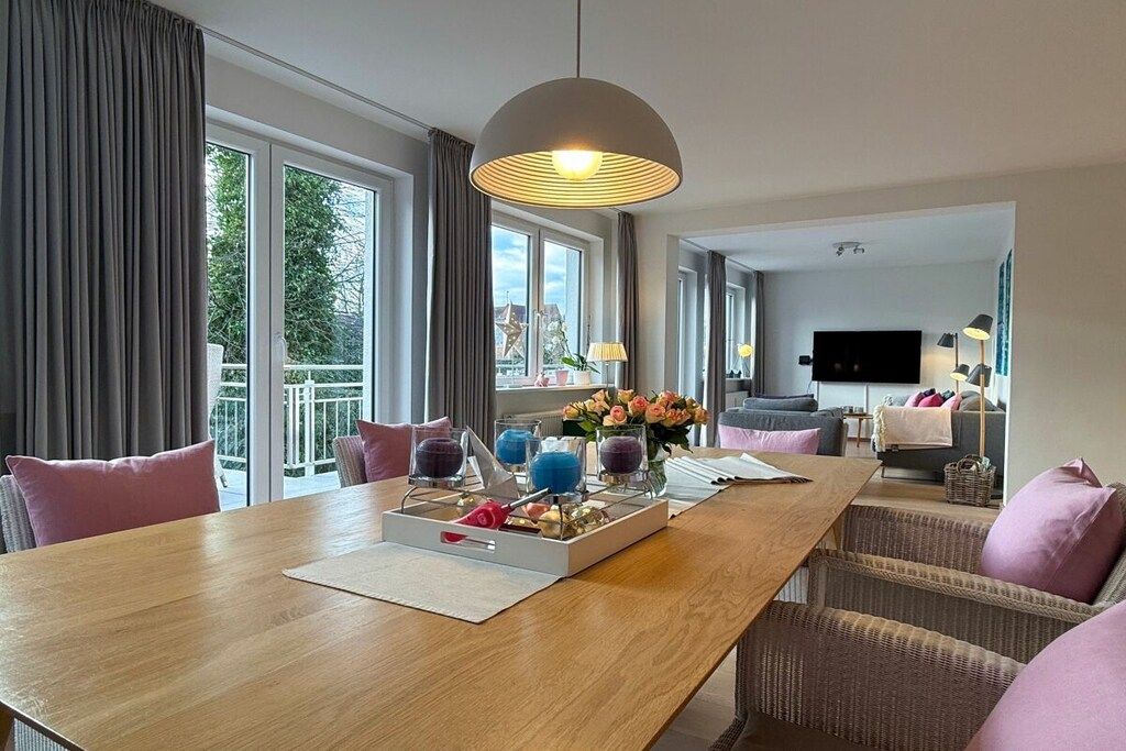 Een hotelkamer met een zithoek, een bank, een televisie en een balkon met gordijnen.