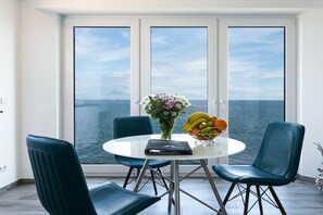 A dining area with a round table, two chairs, a vase with flowers, and a bowl of fruit. - Holiday apartment with 3 bedrooms (Kappeln)