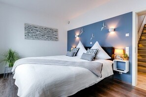 Un dormitorio con una cama, un estante en la pared, una planta y una escalera.