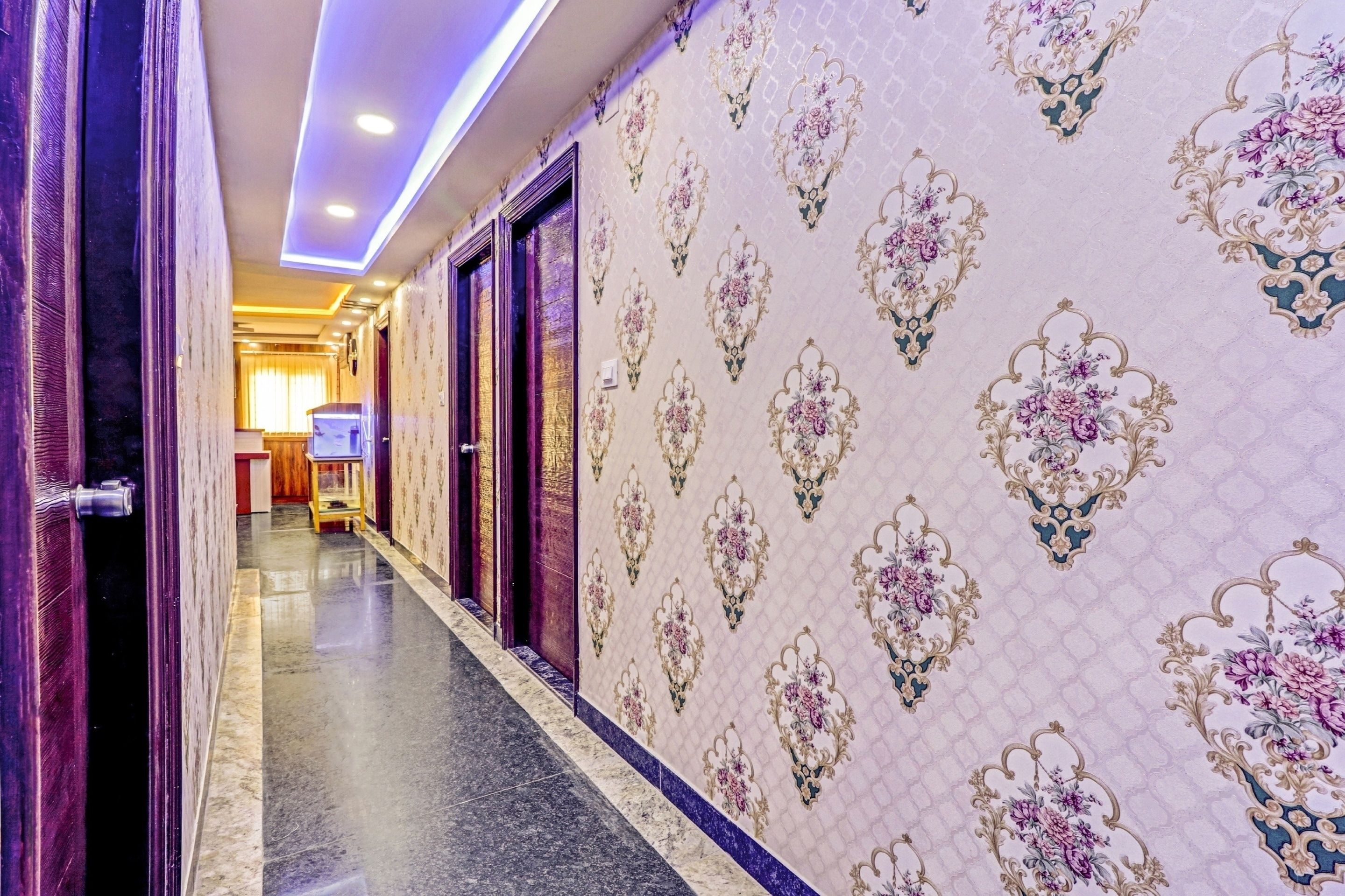 A hallway with patterned wallpaper, a marble floor, and a door leading to another room.