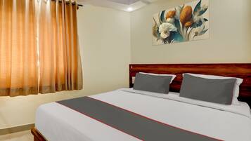 Een hotelkamer met een bed, gordijnen, een schilderij en een houten hoofdeinde.