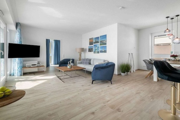 Ein modernes Wohnzimmer mit einer Couch, einem Couchtisch und einem an der Wand befestigten Fernseher.
