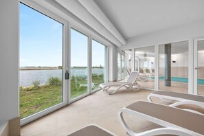 Una habitación de hotel moderna con ventanas amplias, una zona de piscina y un comedor.