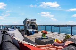A deck with a sofa, a striped chair, and a table with fruit and flowers. - Holiday apartment with 1 bedroom (Olpenitz)