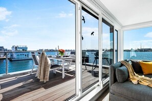 Une terrasse moderne avec une table et des chaises, donnant sur une étendue d’eau.