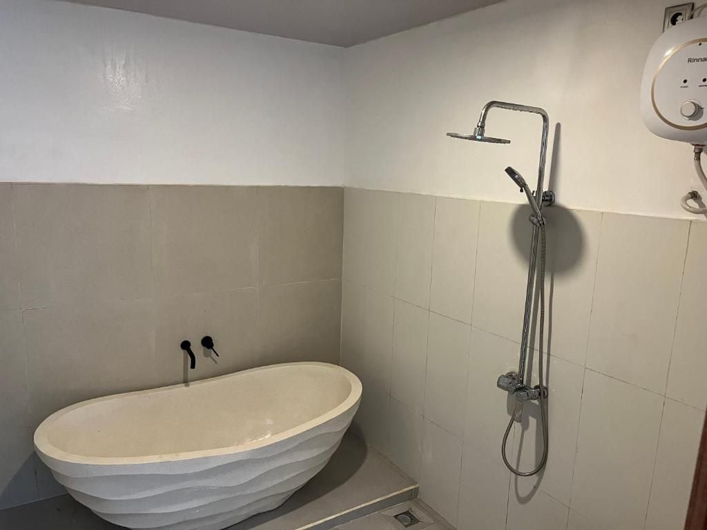 Un baño con una bañera independiente, un cabezal de ducha y un grifo de pared.