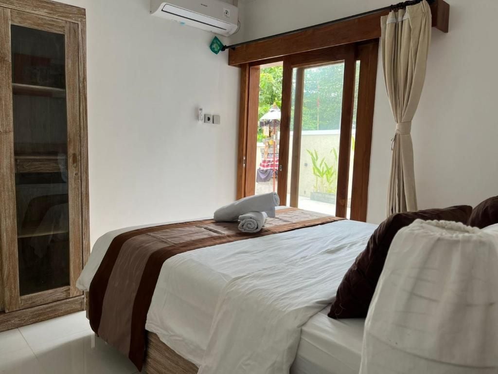 Een slaapkamer met een bed, een raam met gordijnen en een houten deur.