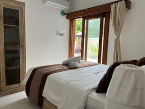 Quarto com cama, janela com cortinas e porta de madeira.