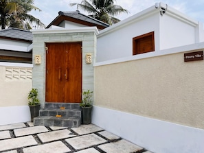 A modern villa entrance with a wooden door, stone steps, and a nameplate reading 'Peony Villa.' - Peony Villa Lovina Private Pool (Sukasada)