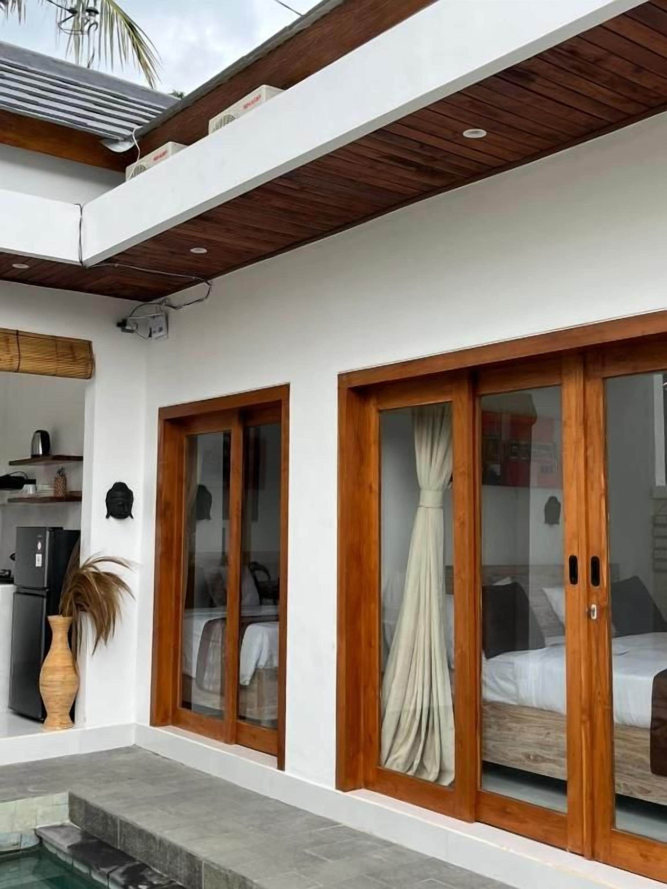 Ein modernes Zimmer mit einem Bett, einem Fenster mit Vorhängen und einer kleinen Küchenzeile.
