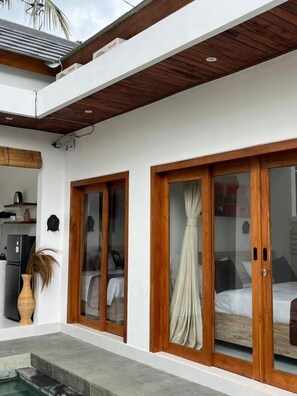 Una habitación moderna con cama, ventana con cortinas y una pequeña cocina.