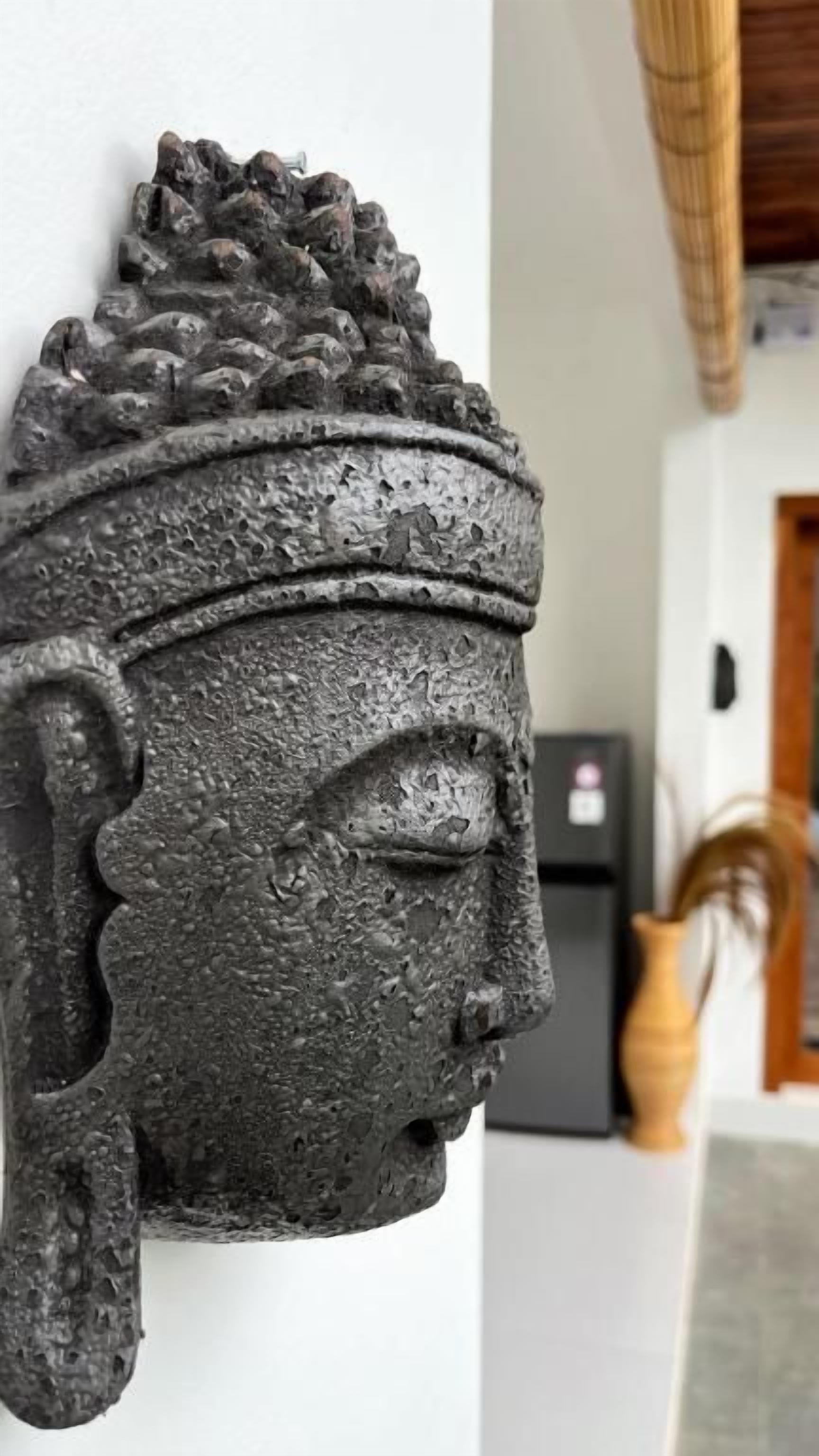 Escultura detalhada fixada na parede, com textura marcante.