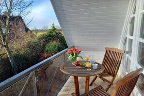 A balcony with a table set for two, a chair, and a vase of flowers. - Holiday apartment in Nieblum with balcony (Nieblum)