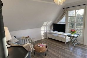 Un salon moderne avec un téléviseur, une table à manger et une fenêtre avec des rideaux.
