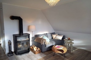 A cozy living room with a fireplace, a sofa, a lamp, and a small table. - Holiday apartment in Nieblum with balcony (Nieblum)