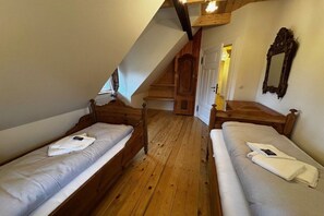 Ein Zimmer mit zwei hölzernen Betten, einer Holztreppe und einem Spiegel an der Wand.