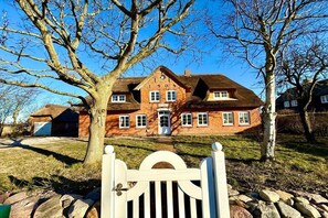 A large brick house with a central door and multiple windows, surrounded by a stone wall and trees. - Det Danske Hus - Apartment Upper Deck (Dunsum)