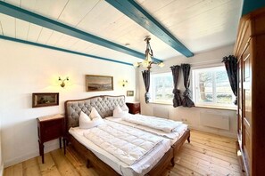 A bedroom with a large bed, a nightstand, a chandelier, and a window with curtains. - Det Danske Hus - apartment on the port side (Dunsum)