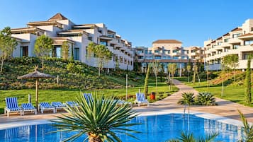 Un resort con piscina, sillas de descanso y jardín ajardinado.