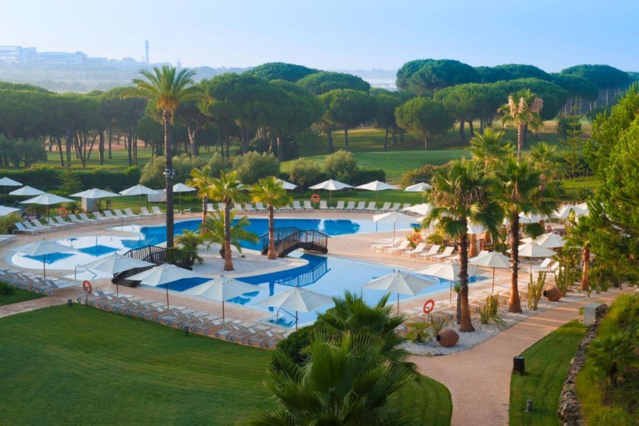 A resort with multiple swimming pools, sun loungers, and palm trees.